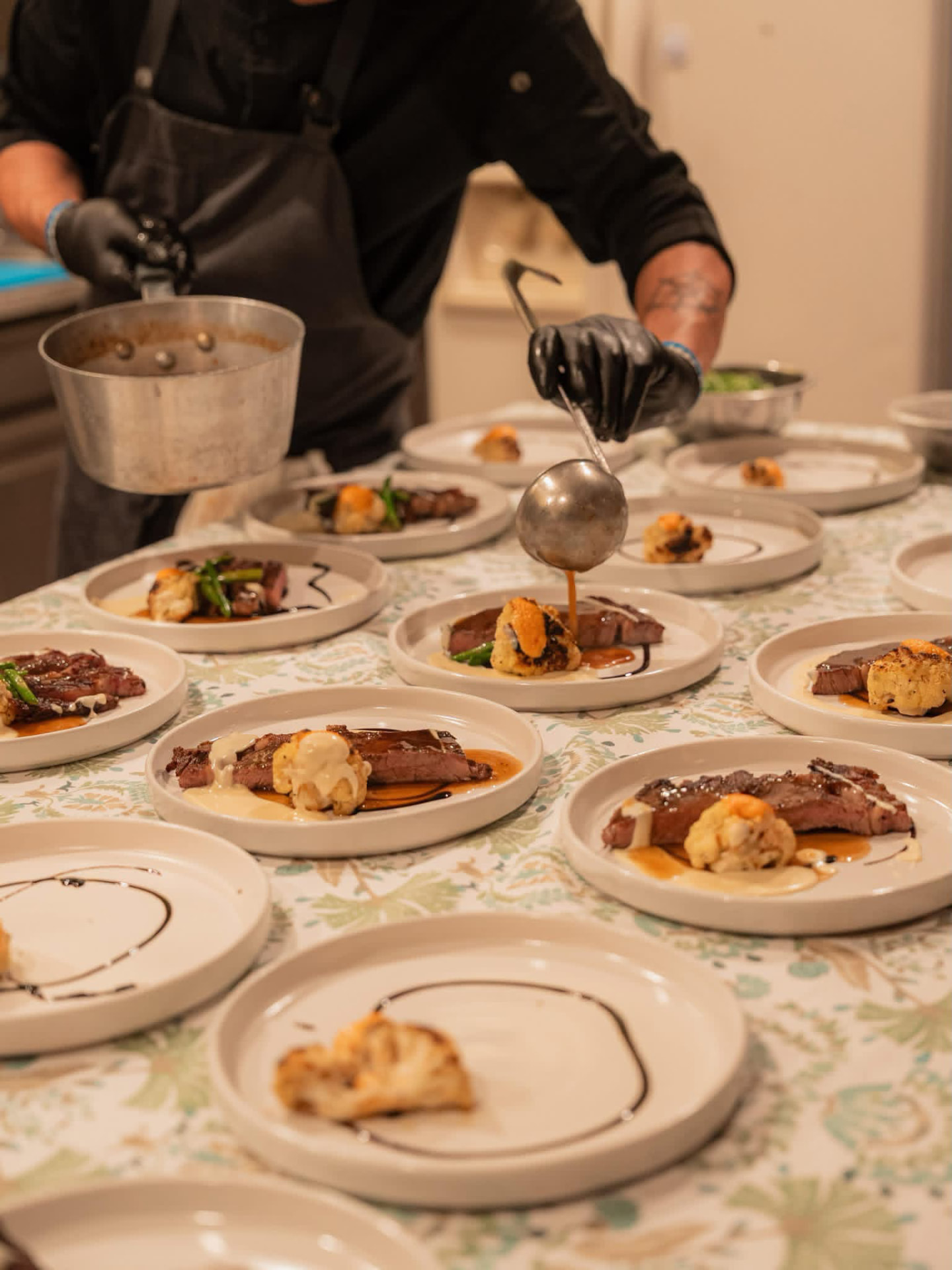 Plated steak dinners being finished by the chef